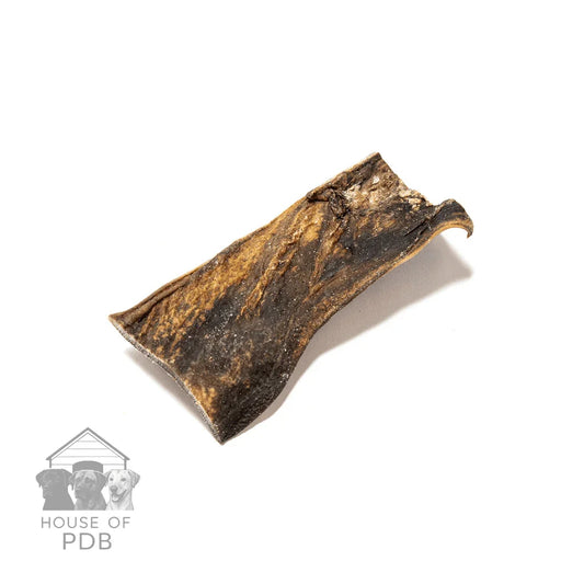 Natural camel skin dog chew with textured brown and black surface on white background